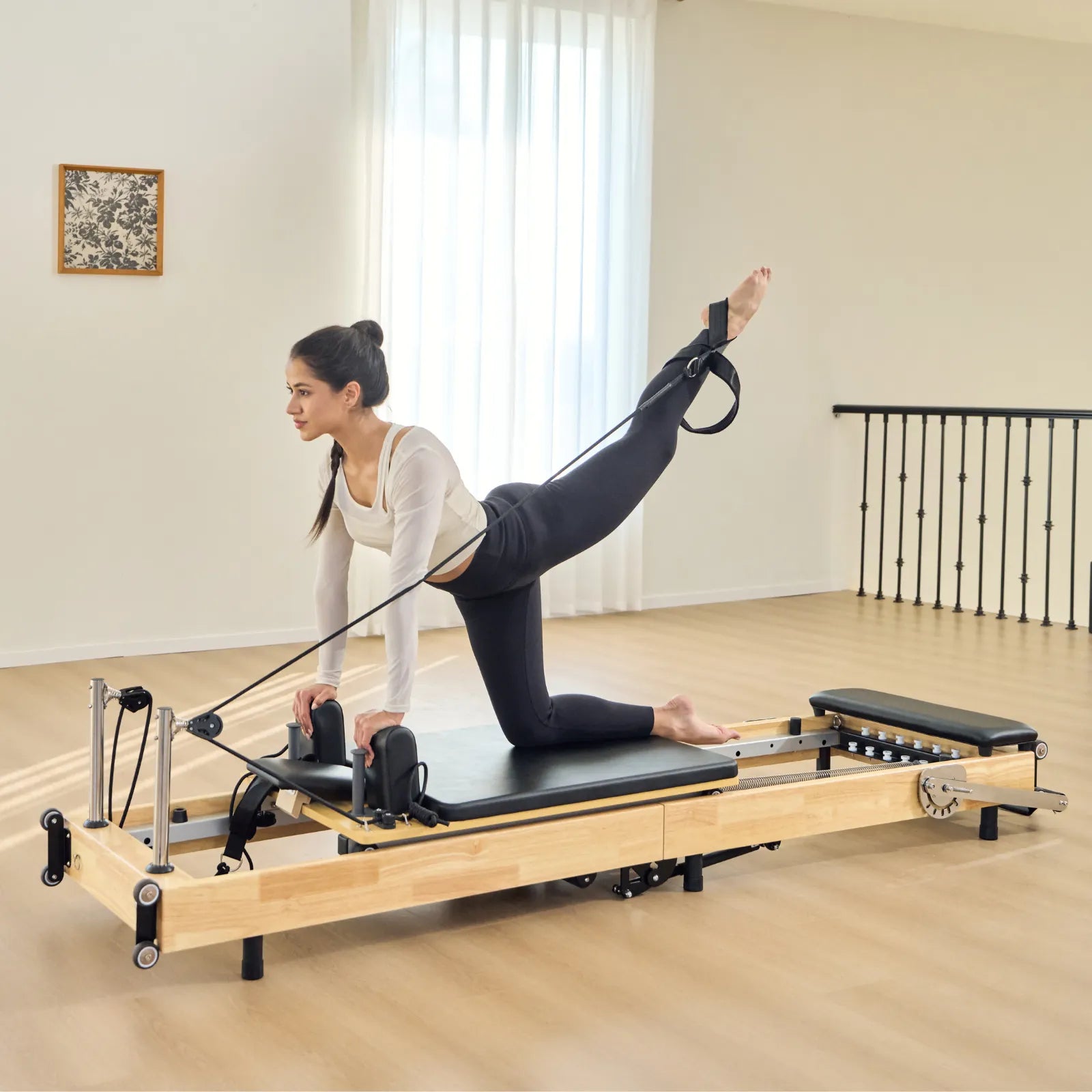 Woman exercising on a Pilates reformer machine in a studio setting.