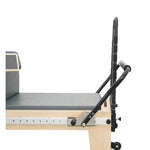 Close-up of the adjustable heavy-duty footbar and high-density padded carriage on the Timber Plus reformer.