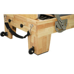Reinforced oak wood base and transport wheels of Grove reformer, durable craftsmanship for heavy use.